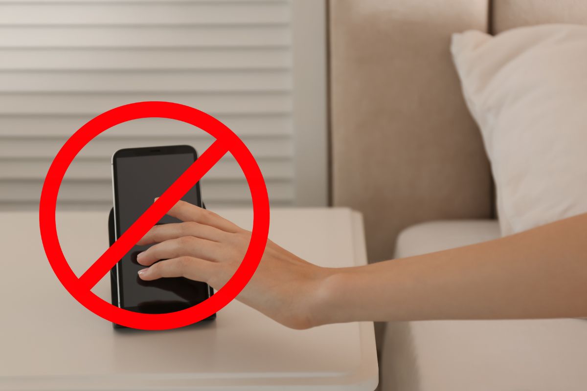 Une main posée sur un smartphone avec un symbole d'interdiction.